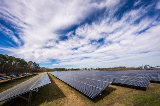 Solar panels spread across a field under a bright blue sky with clouds, showcasing renewable energy.